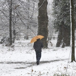 Mann mit einem Regenschirm an einem verschneiten Wintertag 