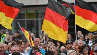 Auf einer öffentlichen Veranstaltung werden Deutschland-Fahnen geschwungen. 