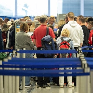 Passagiere stehen auf dem Flughafen Frankfurt an einem Schalter. Die Gewerkschaft Verdi hat die Beschäftigten des öffentlichen Dienstes und der Bodenverkehrsdienste für Montag zu einem 24-stündigen Warnstreik an 13 Flughäfen aufgerufen.