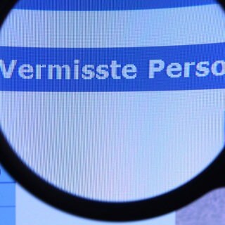 Schriftzug "Vermisste Person" unter Lupe