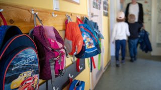 Kinderrucksäcke hängen im Eingangsbereich eines Kindergartens.