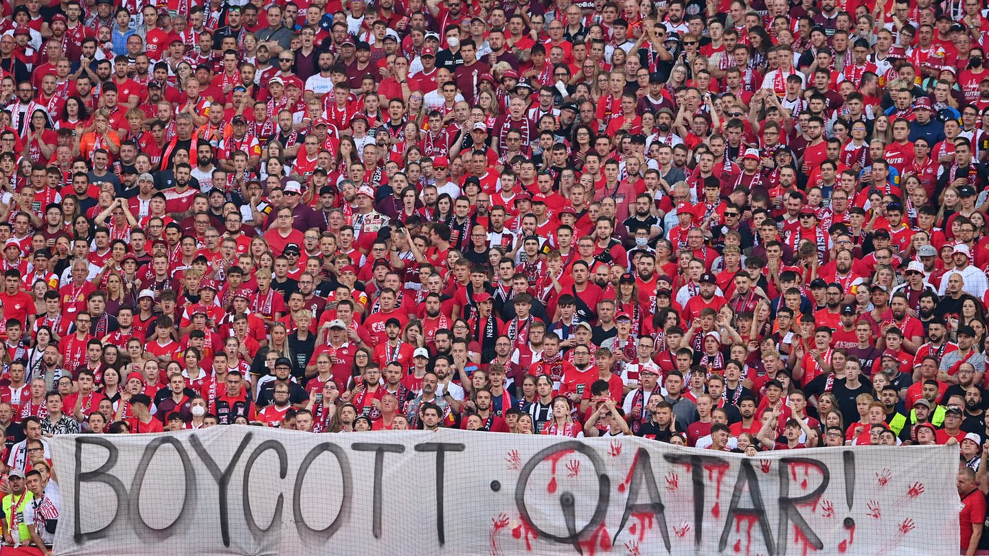 Fans halten ein Banner hoch auf dem steht, dass die WM in Katar boykottiert werden soll