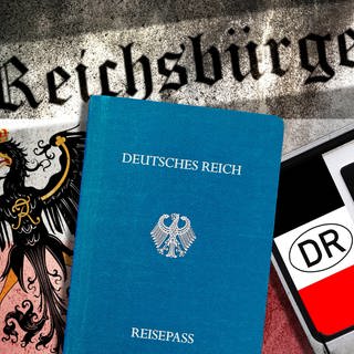 Reichsbürger-Pässe, Reichsadler und Reichsbürger-Nummernschild. (Symbolfoto)