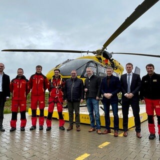 Landräte und Rettungsteam stehen vor dem Rettungshubschrauber "Christoph 66".