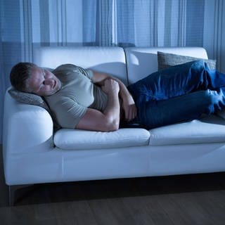 Ein Mann schläft auf einer Couch