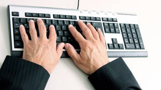 Mann aus Kaiserslautern um mehrere Zehntausend Euro betrogen - Hände auf Computertastatur