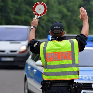 Ein Polizist hält ein Auto an: Die Polizei im Westen der Pfalz hat mehr als 500 Autofahrer auf Alkohol und Drogen kontrolliert. Dabei wurden diverse Verstöße festgestellt.