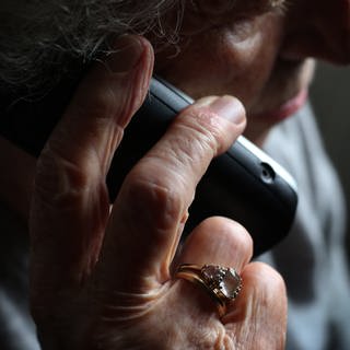Frau aus Kaiserslautern verliert 50.000 Euro durch Schockanruf - Frau hält Telefonhörer in der Hand