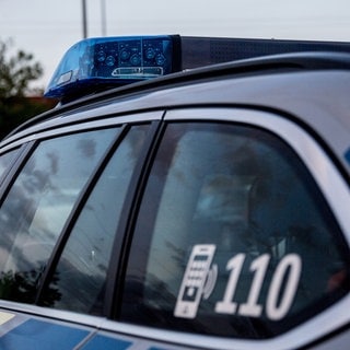 Nachbar in Pirmasens schwer mit Metallstange verletzt - Polizeiauto mit Blaulicht an einer Straße