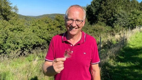 Den ganzen Laufvogel haben sie nicht erwischt, aber immerhin eine Feder. Der Ortsbürgermeister von Bann, Stephen Mees (CDU), mit einer Feder des entlaufenen, frechen Emus.