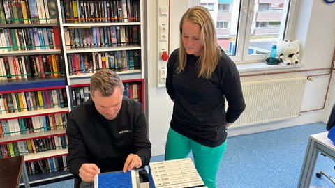 Mirjam Färber zeigt ihrem Austauschkollegen Christopher Lamprecht in den Westpfalz-Werkstätten in Kaiserslautern, was er zu tun hat. 