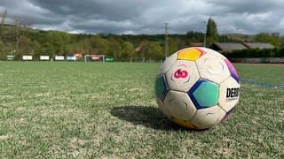 Fußball liegt auf Kunstrasen auf einem Sportplatz.