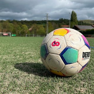 Fußball liegt auf Kunstrasen auf einem Sportplatz.