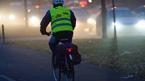 Polizei Kaiserslautern gibt Tipps für Straßenverkehr in dunkler Jahreszeit - Radfahrer mit Warnweste auf dunkler Straße