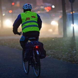 Polizei Kaiserslautern gibt Tipps für Straßenverkehr in dunkler Jahreszeit - Radfahrer mit Warnweste auf dunkler Straße