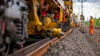 Streit zwischen Zweckverband und Bahn über Bauarbeiten bei Zweibrücken - Baumaschine arbeitet an Gleisen