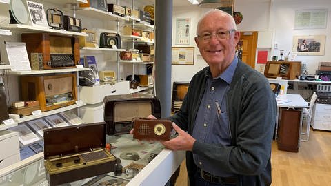 Mann hält kleines Radio in der Hand - Radiomuseum Obermoschel zu 100 Jahre Radio