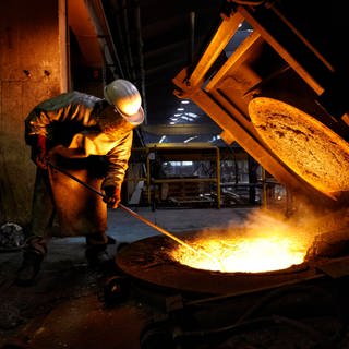 Arbeiter in einer Gießerei an Behälter mit flüssigem Eisen