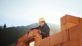 Handwerker mit Helm stapelt Bausteine 