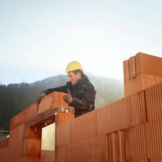 Handwerker mit Helm stapelt Bausteine 