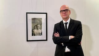 Der Fotomedia-Künstler Boris Eldagsen neben seinem Bild "Electrician", das mit Hilfe Künstlicher Intelligenz (KI) generiert wurde.