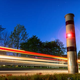 Eine Blitzersäule blitzt mit rotem Licht