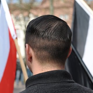 Ein Mann steht mit einer Nazi-Flagge bei einer Kundgebung.