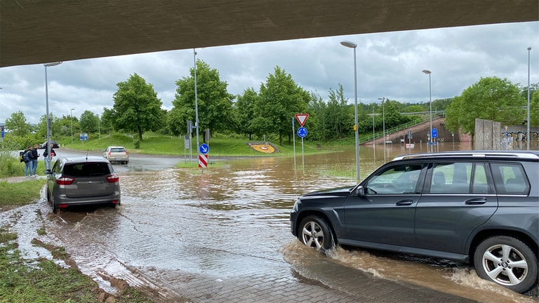 Im Bubenhausener Kreisel in Zweibrücken steht Wasser - Autos fahren durch.