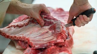 Schlachthof Zweibrücken schlachtet vorerst nicht - ein Schlachter arbeitet an einer Schweineschulter