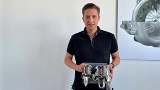 Andreas Denne leitet das BorgWarner-Werk in Kirchheimbolanden. In der Hand hält er das Modell eines E-Boosters. Das ist ein elektrisch angetriebener Verdichter. 
