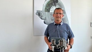 Peter Schmitt ist der Betriebsratsvorsitzende des Borg-Warner-Werks in Kirchheimbolanden. In der Hand hält er das Modell eines E-Boosters. Das ist ein elektrisch angetriebener Verdichter. 