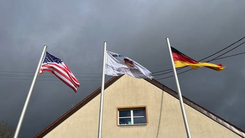 Drei Fahnen - eine deutsche, eine amerikanische und die Fahne der Veteranen-Initiative - wehen im Wind.