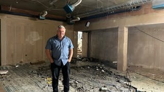 Thomas Schiwek, Eigentümer und Projektinitiator, steht in dem Keller der Parkklinik, wo der ganze Parkettboden zerstört wurde, auch Kabel hängen von der Decke. (SWR)