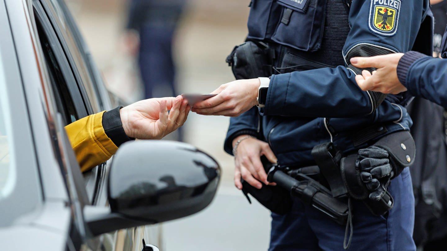 Polizist kontrolliert die Papiere eines Autofahrers
