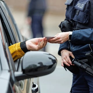 Polizist kontrolliert die Papiere eines Autofahrers