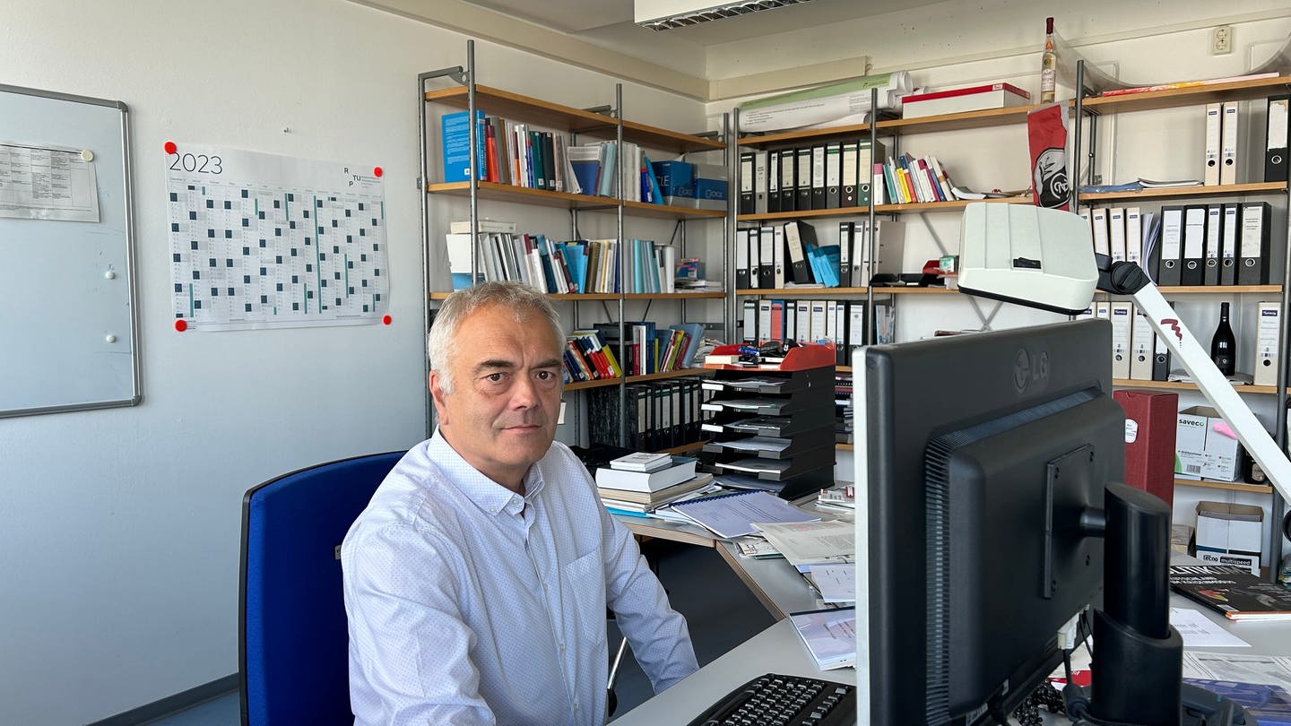 Prof. Marcus Höreth von der Uni Kaiserslautern, sitzt in seinem Büro am Schreibtisch, hinter ihm und an der Seite der Wand stehen Bücherregale. (SWR)
