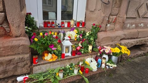Vor der Wohnung einer getöteten Frau in Reichenbach-Steegen im Kreis Kaiserslautern haben Menschen Blumen abgelegt.