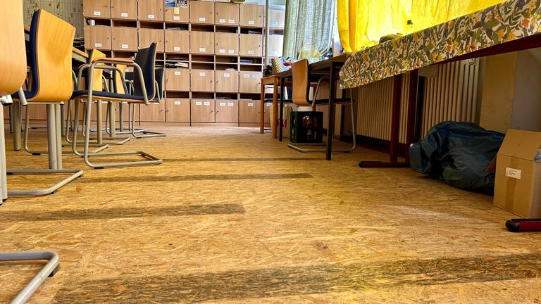 Im Lehrerzimmer sind Holzbauplatten über dem beschädigten Holzboden verschraubt.