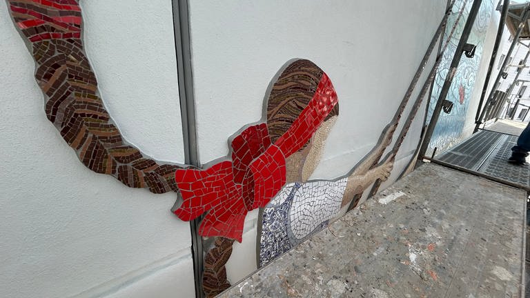 Auf dem Mosaik an der Münztreppe in Pirmasens schwingt ein Mädchen auf einer Schaukel