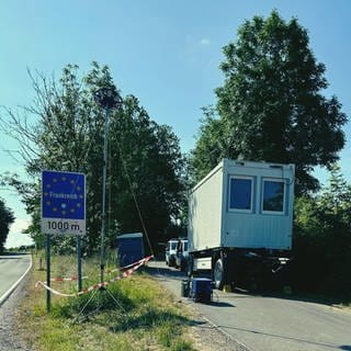 Grenzübergang zu Frankreich bei Hornbach in der Südwestpfalz ist zu sehen. Im Hintergrund neben der Straße zwei Polizeiautos und ein Container.