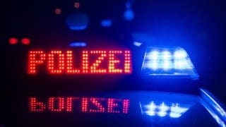 Blaulicht Polizei und zwei Polizisten im Hintergrund - die Polizei hat in Kaiserslautern nach einem Vermissten gesucht