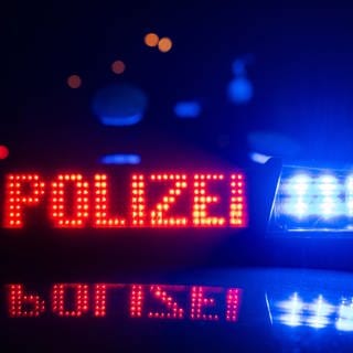 Blaulicht Polizei und zwei Polizisten im Hintergrund - die Polizei hat in Kaiserslautern nach einem Vermissten gesucht