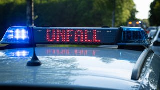 Ein Einsatzfahrzeug, Streifenwagen, der Polizei steht mit Blaulicht und dem Schriftzug Unfall im Display an einem Unfallort.