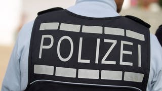 Polizist in Unfiform mit der Aufschrift "Polizei" auf der Weste