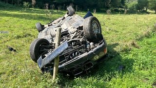 Nach einem Unfall durch einen Fahranfänger bei Altenglan (Kreis Kusel) zerstörtes Auto in einer Wiese auf dem Dach liegend