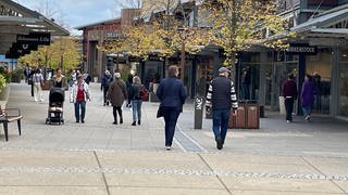 Besucher schlendern an den Geschäften des Fashion Outlet in Zweibrücken vorbei