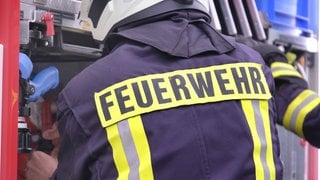 Feuerwehrmann steht an einem Fahrzeug der Feuerwehr - Brand in einer Lagerhalle in St. Alban im Donnersbergkreis