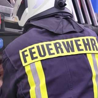 Feuerwehrmann steht an einem Fahrzeug der Feuerwehr - Brand in einer Lagerhalle in St. Alban im Donnersbergkreis