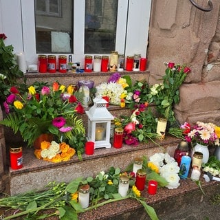 Vor der Wohnung einer getöteten Frau in Reichenbach-Steegen im Kreis Kaiserslautern hatten Menschen kurz nach der Tat Blumen abgelegt (Archivbild).