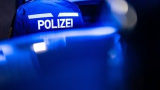 blaulicht und Polizist in Uniform bei Nacht - Symbolbild für Polizei ermittelt nach Kellerbränden auf Brandstiftung in Kaiserslautern